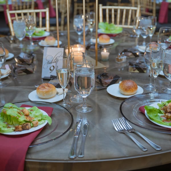 Elegantly set dining table with salads, bread rolls, champagne, and candles at Lattitude Restaurant.