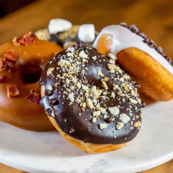 A close-up of assorted Lattitude Restaurant donuts, including chocolate, caramel bacon, and s'mores.