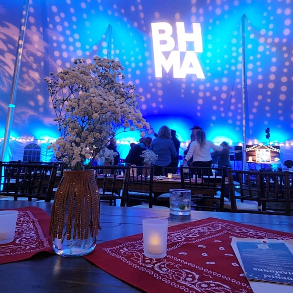A Lattitude Restaurant event with blue lighting, a floral centerpiece, and people mingling.