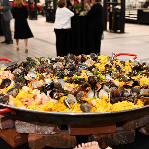 Large paella pan filled with yellow rice, mussels, clams, and shrimp, at a Lattitude Restaurant event.