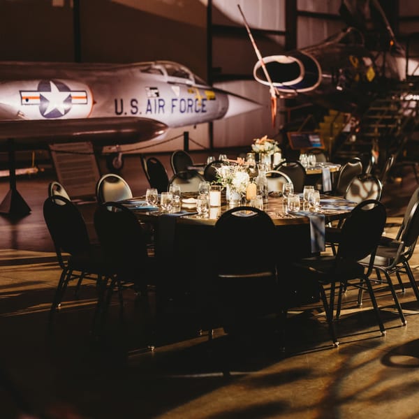 Dining tables set with flowers and candles, with a U.S. Air Force jet in the background.